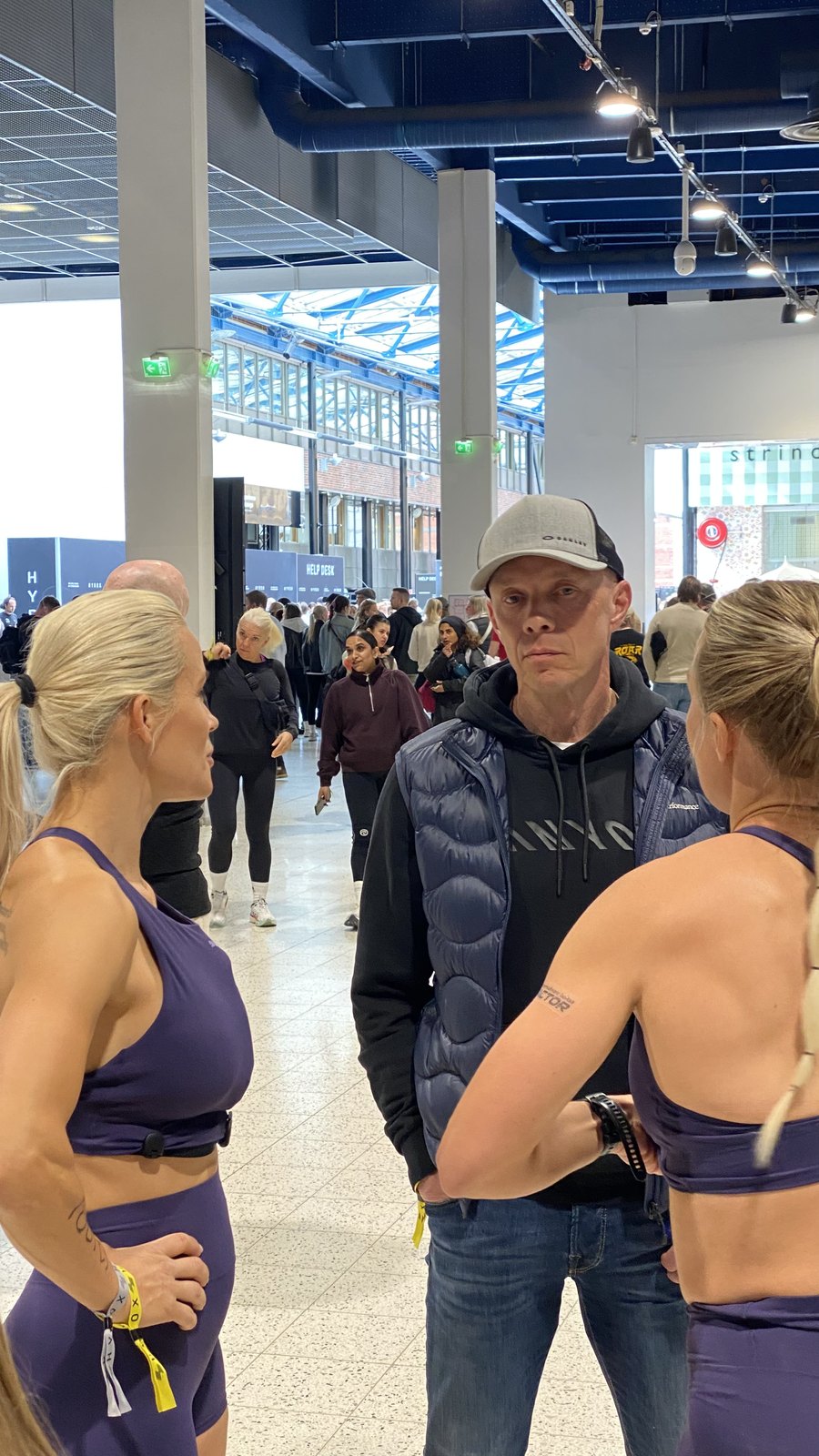 Kilpailijat ja valmentaja keskustelevat HYROX Helsingin kilpailualueella ennen starttia